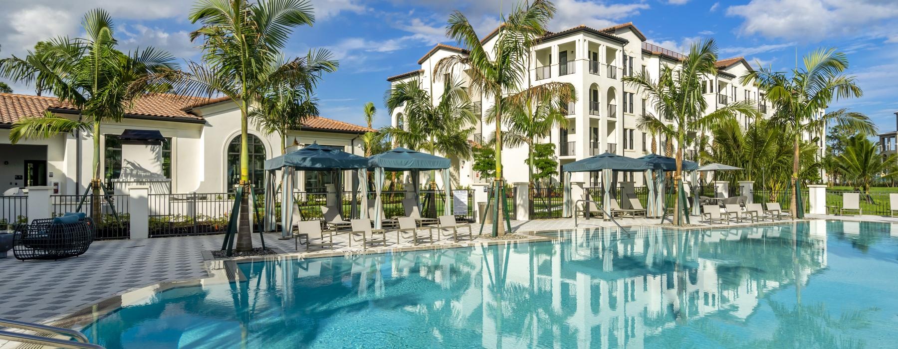 a pool with palm trees and a building in the background