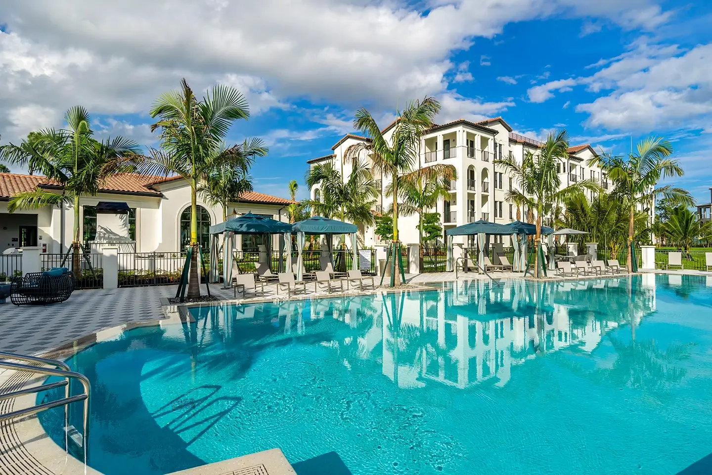 Large community resort-style pool with covered lounge seating and palm trees